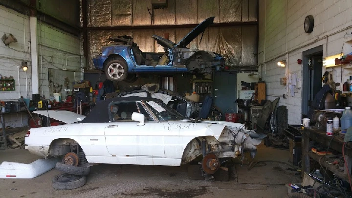 Car workshop with various dismantled vehicles.