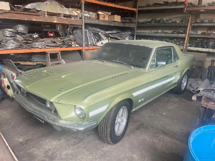 Classic green Mustang in a parts warehouse.