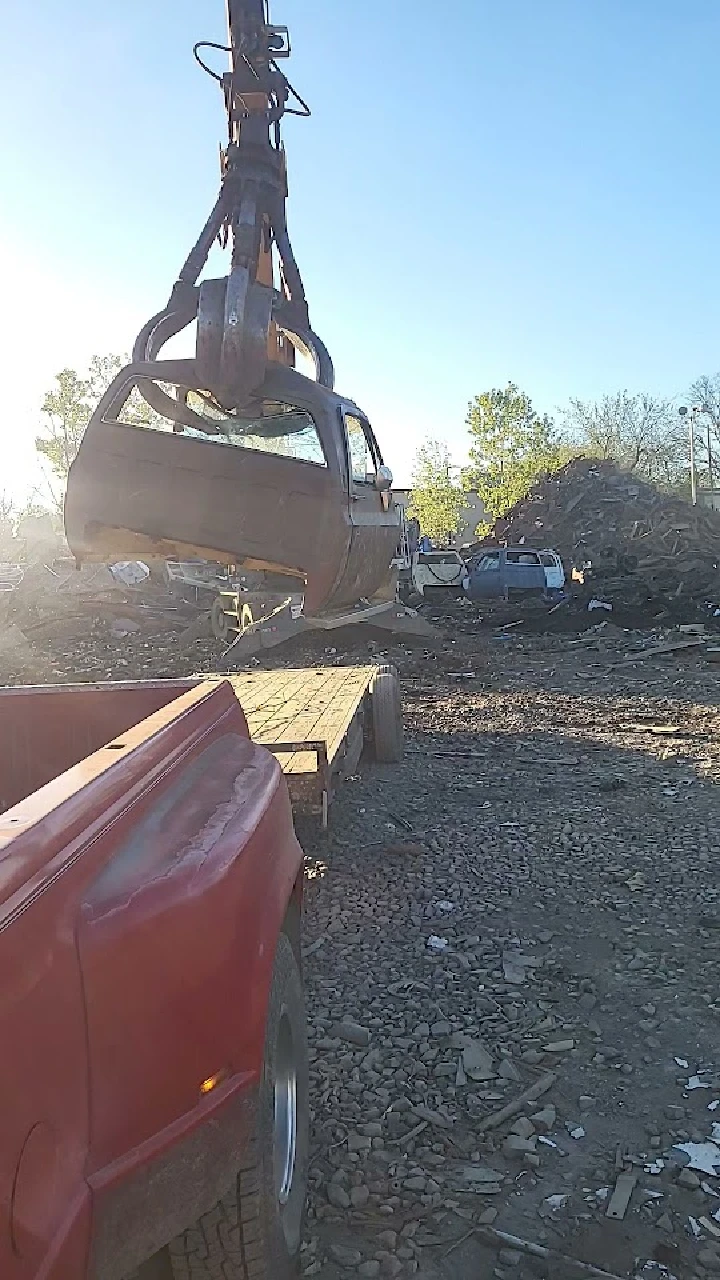 Crane lifting a truck at a metal recycling yard.