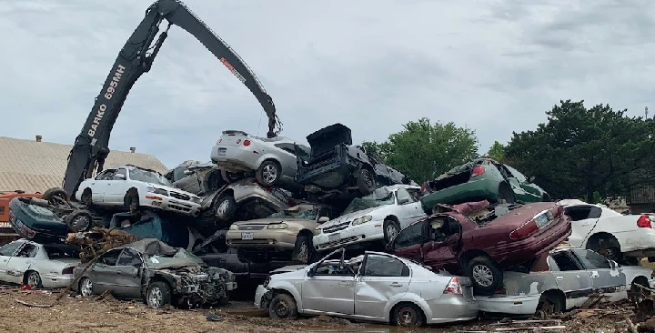 Cranes sorting vehicles at a metal recycling yard.