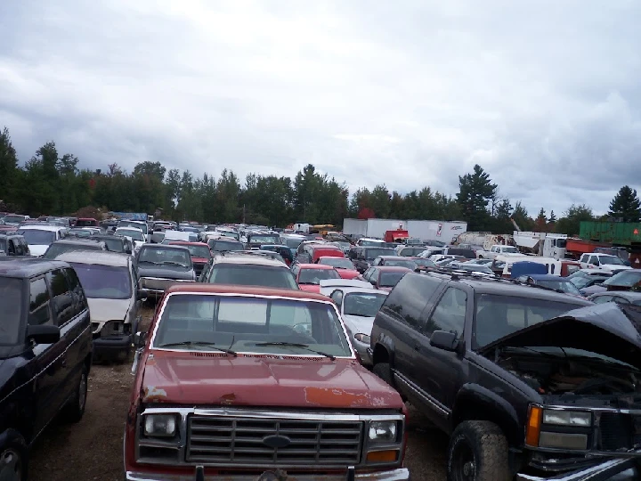 Crowded auto recycling yard with various vehicles.