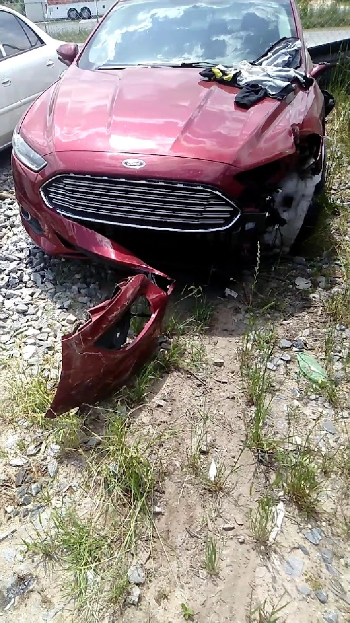 Damaged red car with a missing front bumper.