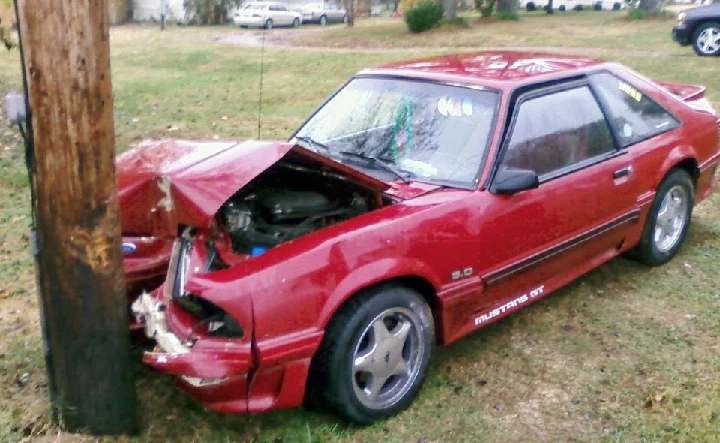 Damaged red Mustang crashed into a utility pole.