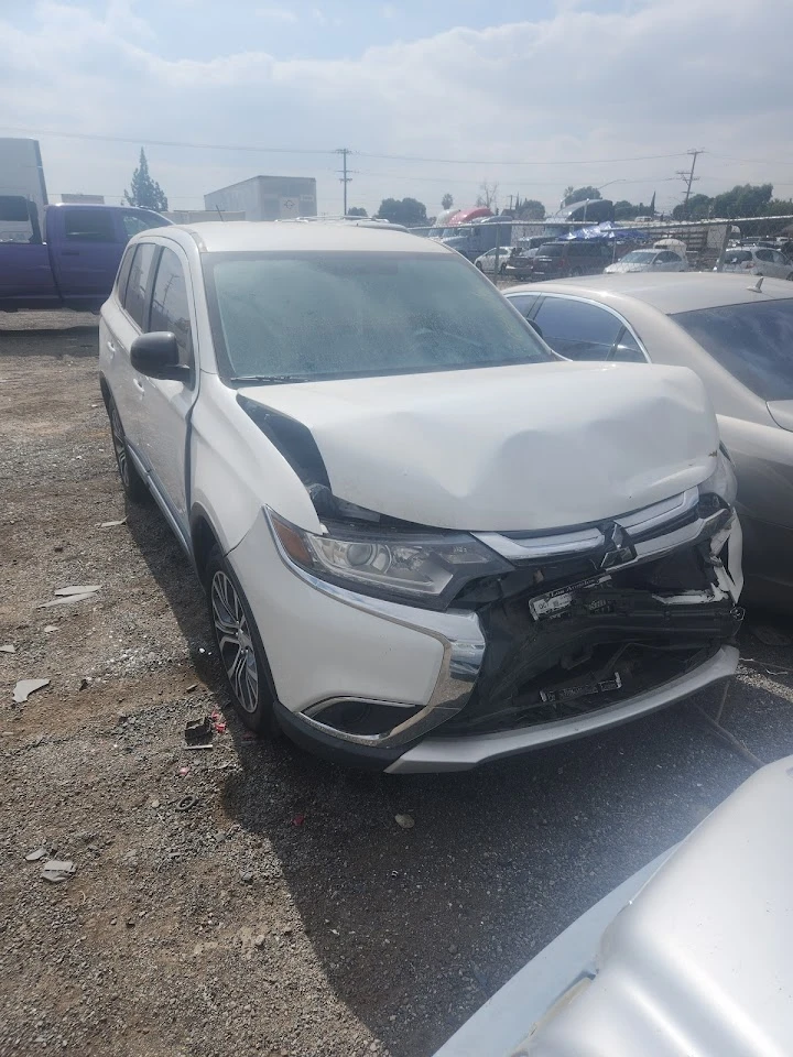 Damaged white SUV in a towing yard.