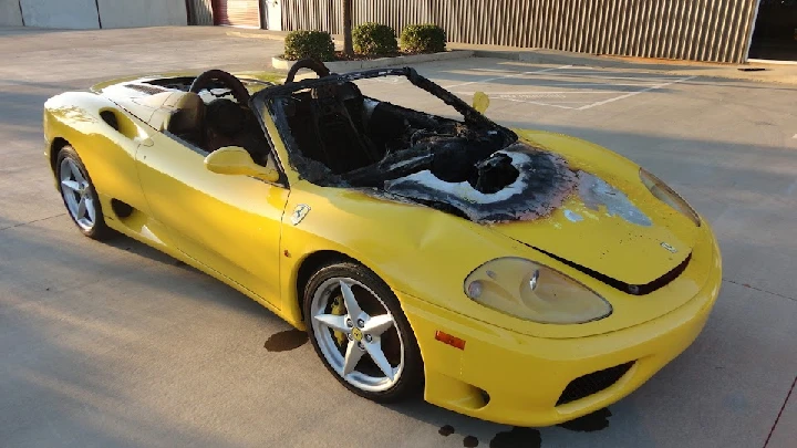 Damaged yellow sports car with burnt interior.