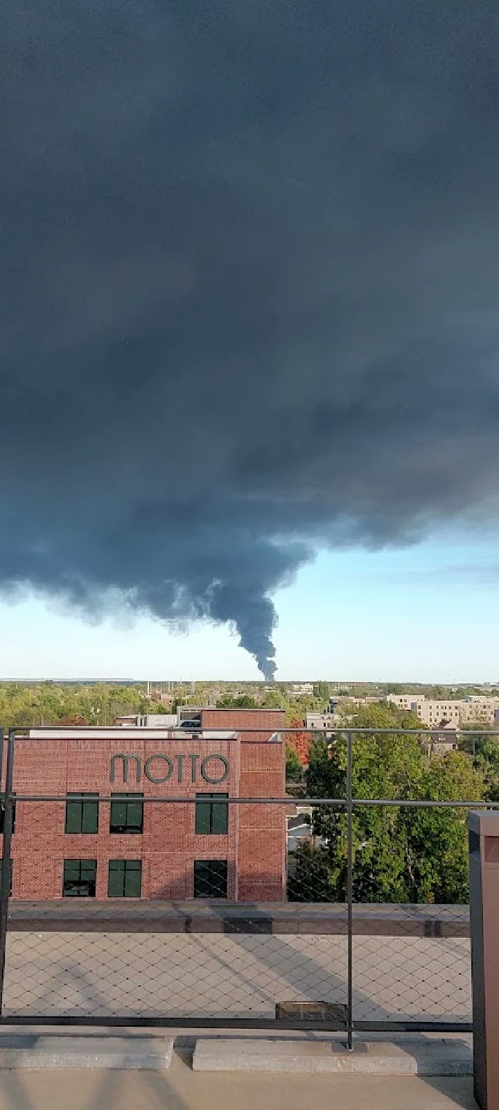 Dark smoke rising over urban landscape.