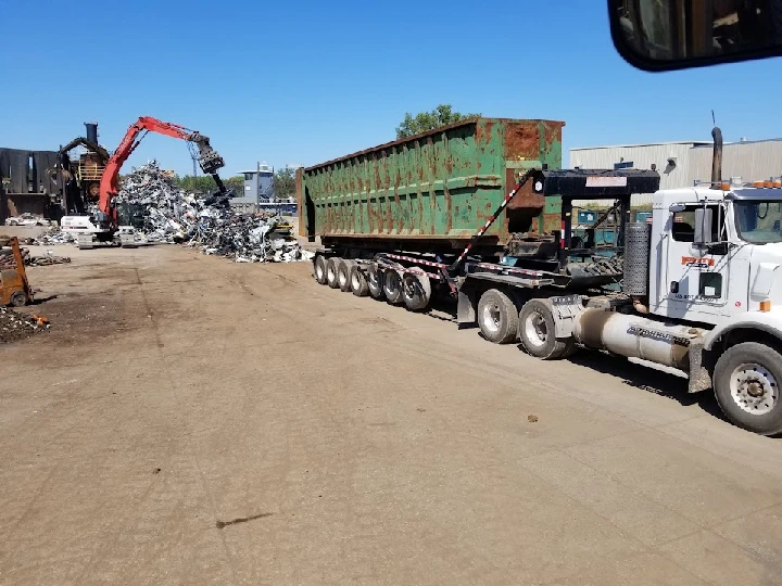 Dump truck and excavator at a scrap metal yard.