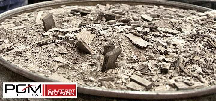 Dusty materials in a metal tray, with branding logo.