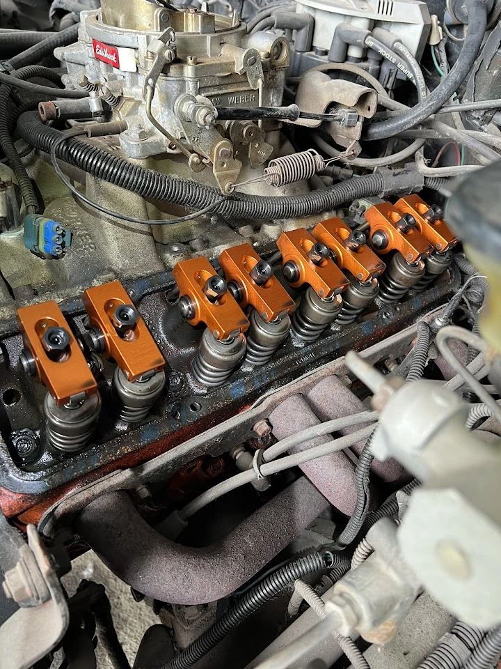 Engine components with orange rocker arms and wiring.