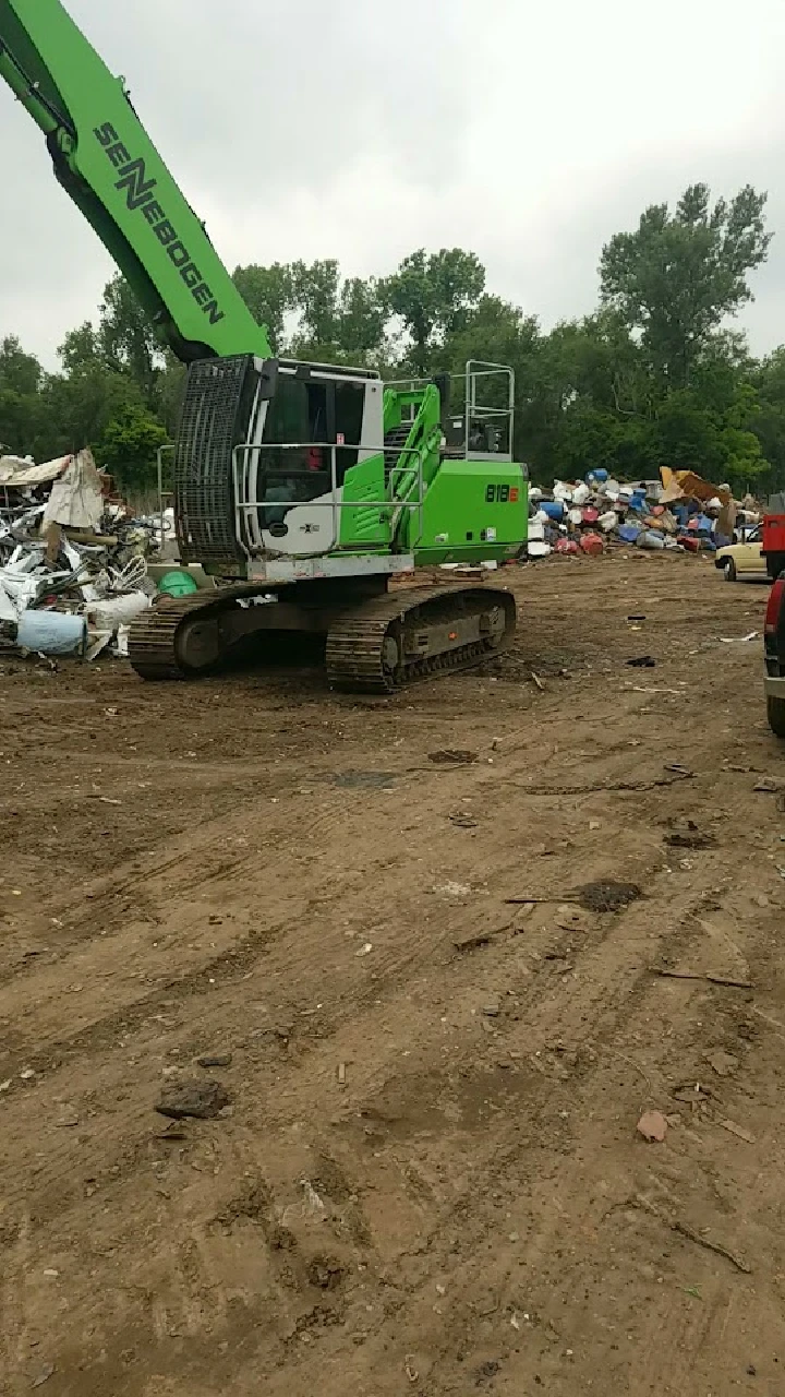 Excavator in a junkyard for vehicle recycling.