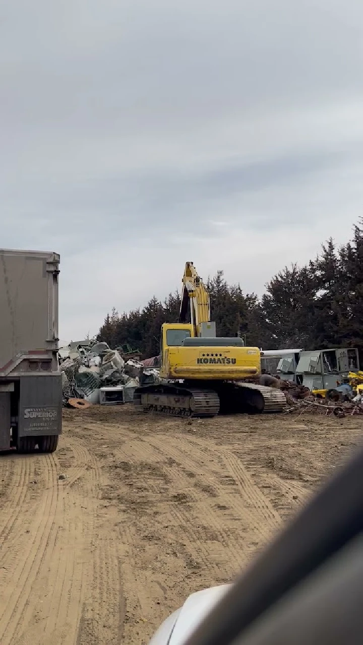 Excavator at Stapleton Salvage yard amidst debris.