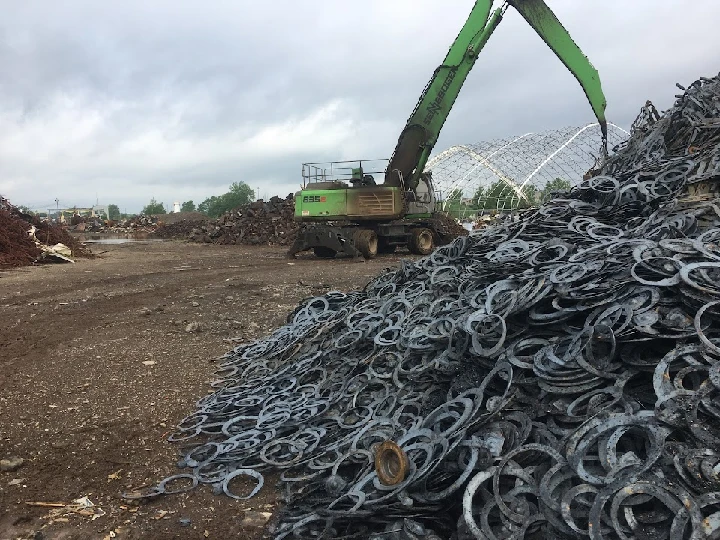 Excavator working among large metal scrap piles.