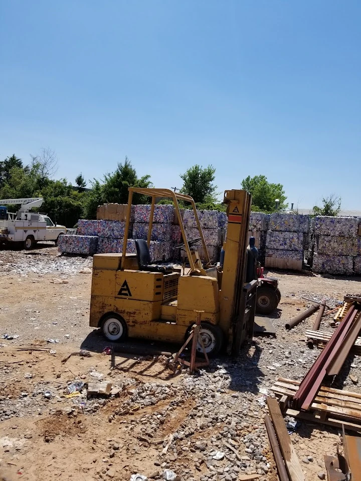 Forklift in a metal recycling yard under blue sky.