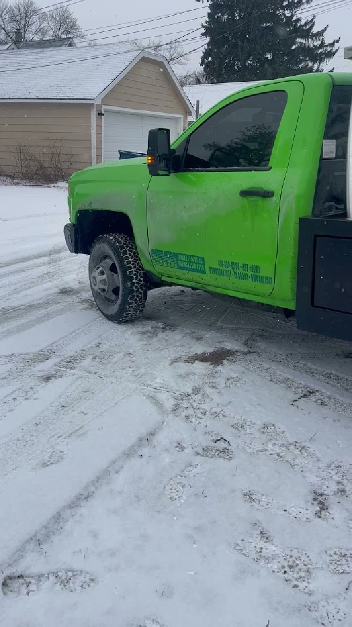 Green towing truck in snowy conditions.