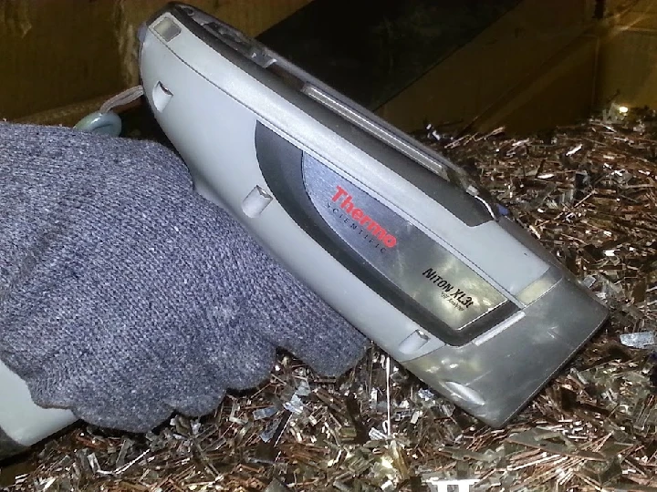 Handheld metal analyzer on a pile of shavings.