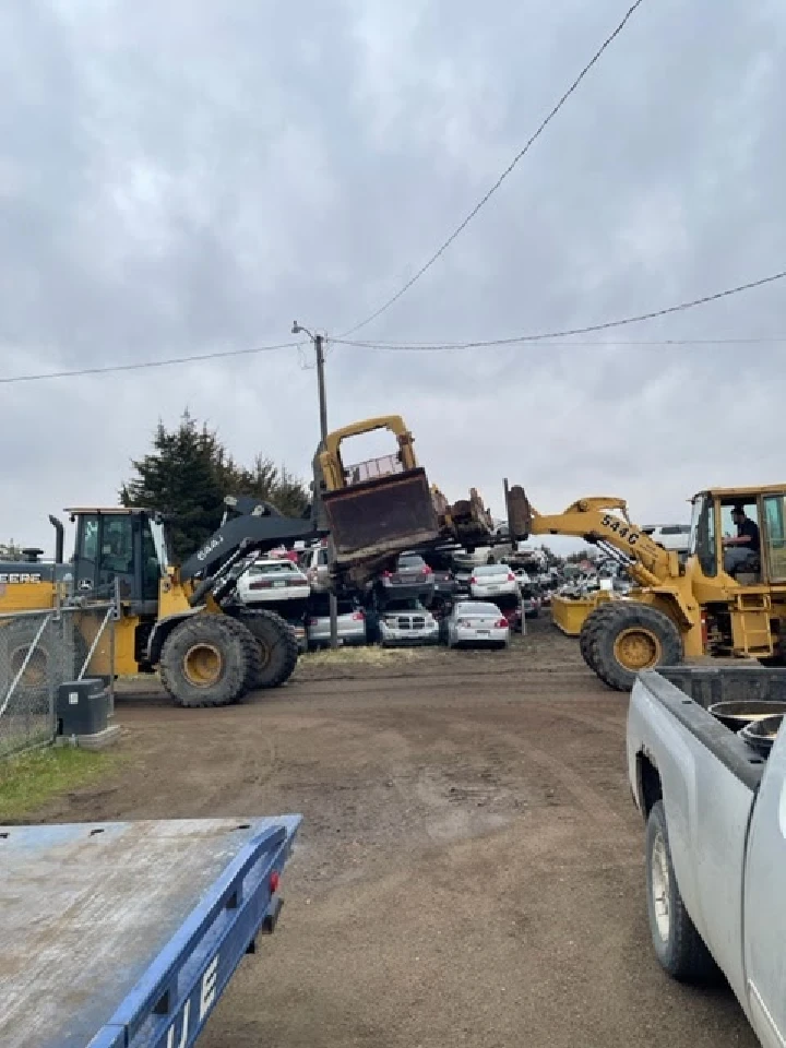 Heavy machinery moving vehicles at a salvage yard.