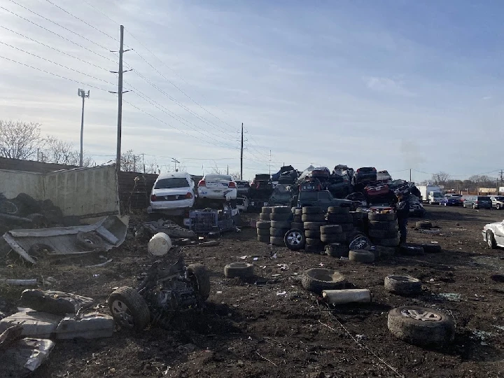 Junkyard filled with stacked cars and old tires.