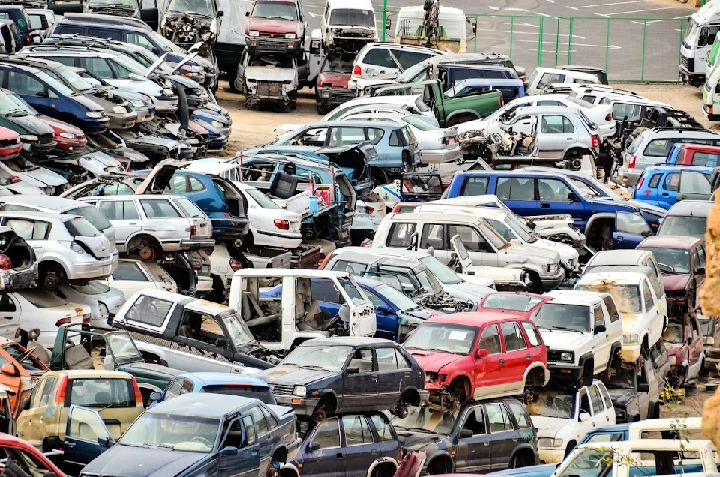 Junkyard filled with various used cars for parts.