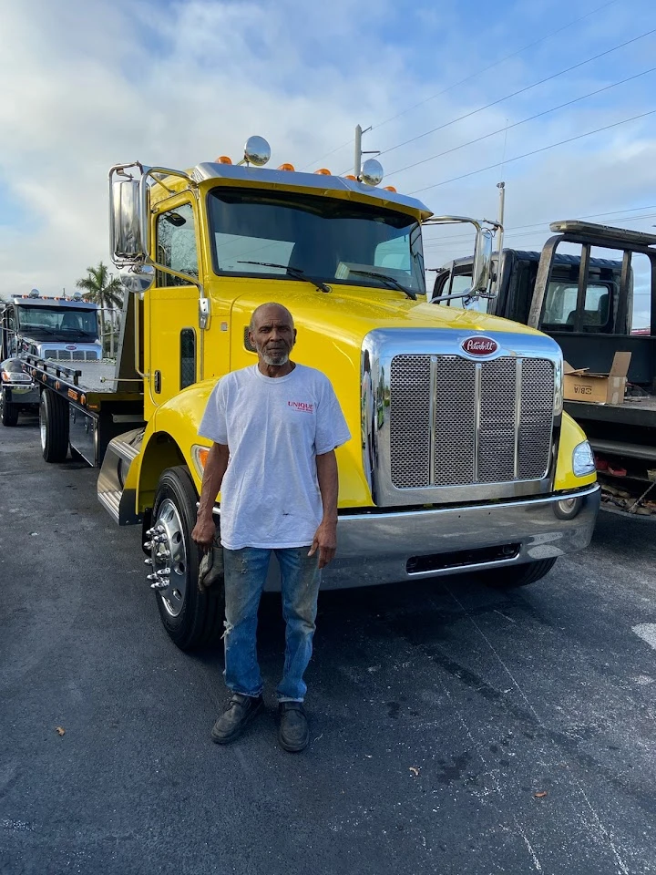 Man standing in front of a yellow tow truck.