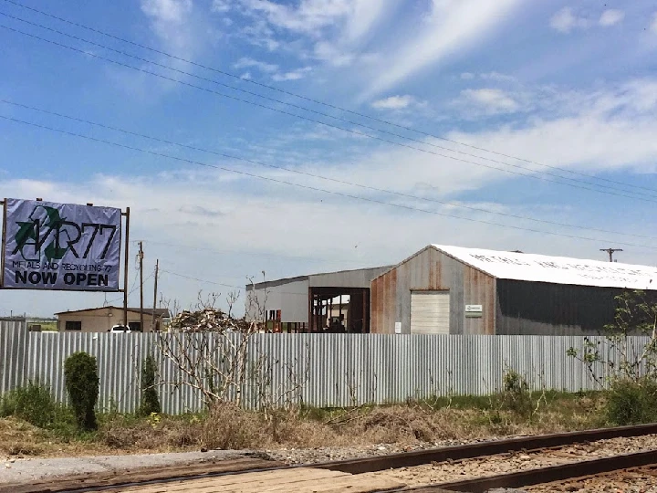 Metal recycling facility with Now Open banner.