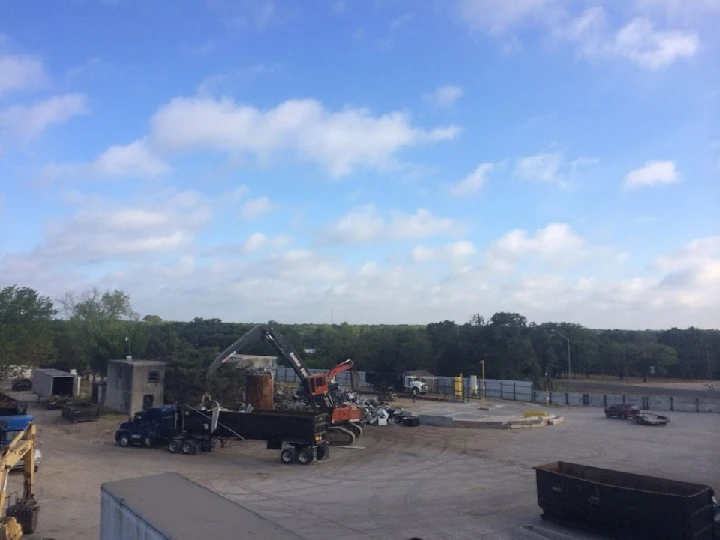 Metal recycling yard with trucks and machinery.