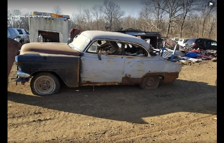 Old rusted car in salvage yard.