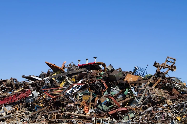 Piled scrap metal against a clear blue sky.