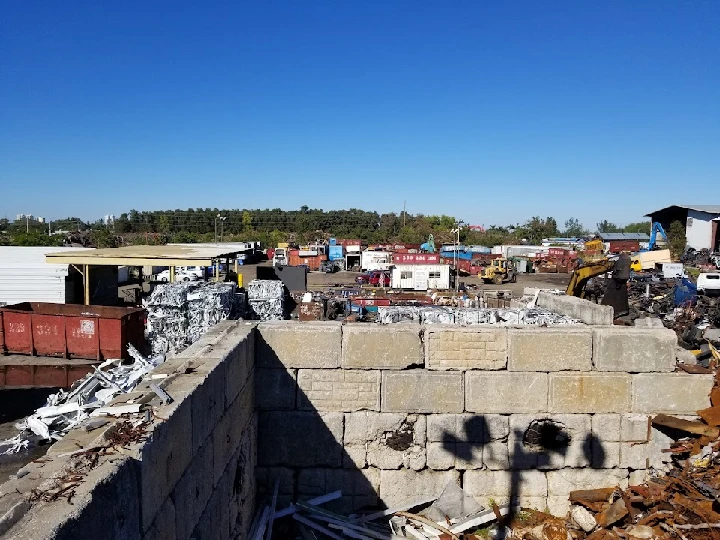 Recycling yard with stacked metals and machinery.