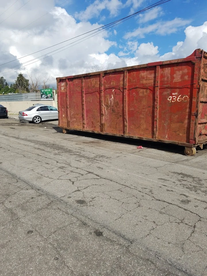 Red dumpster in an auto parts yard.