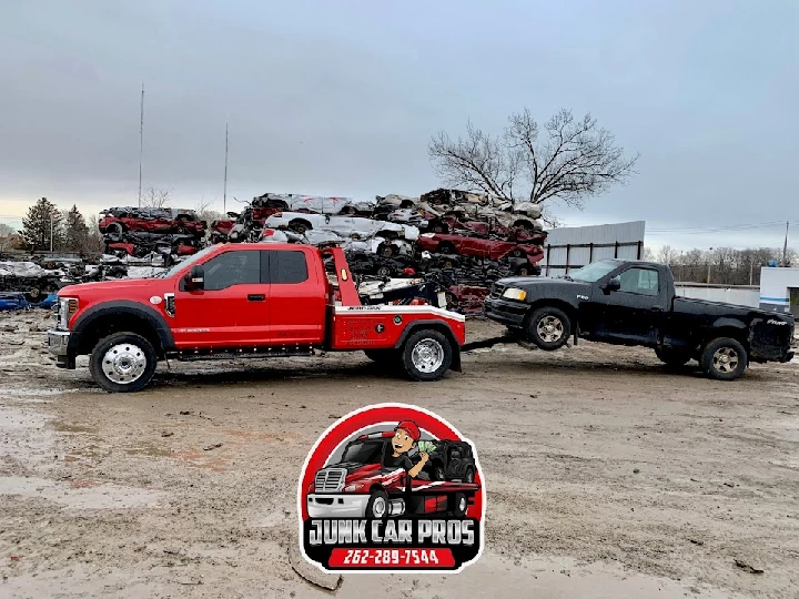 Red tow truck transporting a junk car for cash.