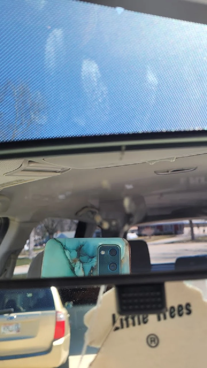 Reflection in a car mirror with a phone visible.