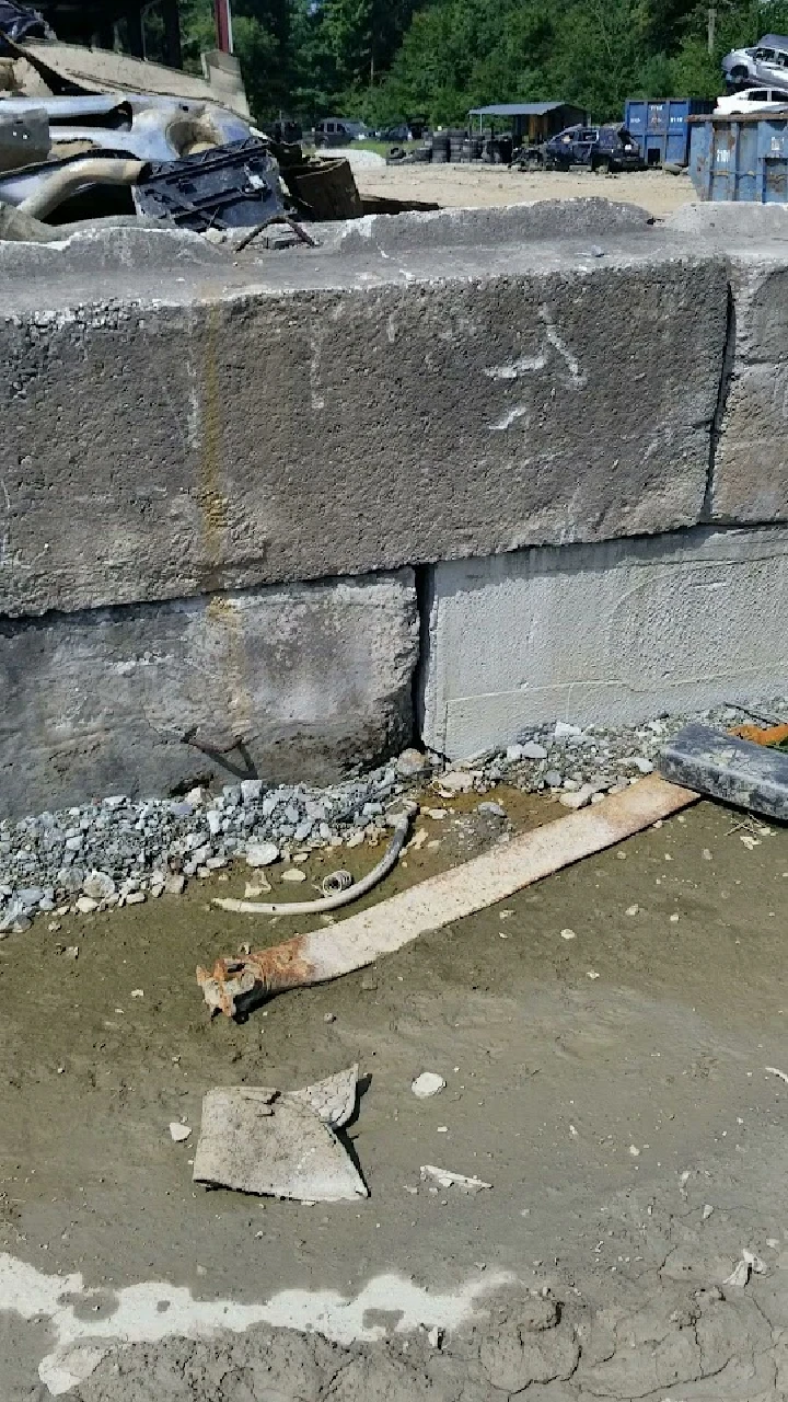 Rusty metal and debris near a concrete barrier.