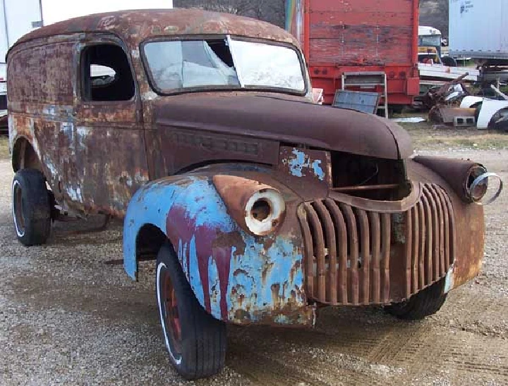 Rusty vintage truck with peeling blue and brown paint.