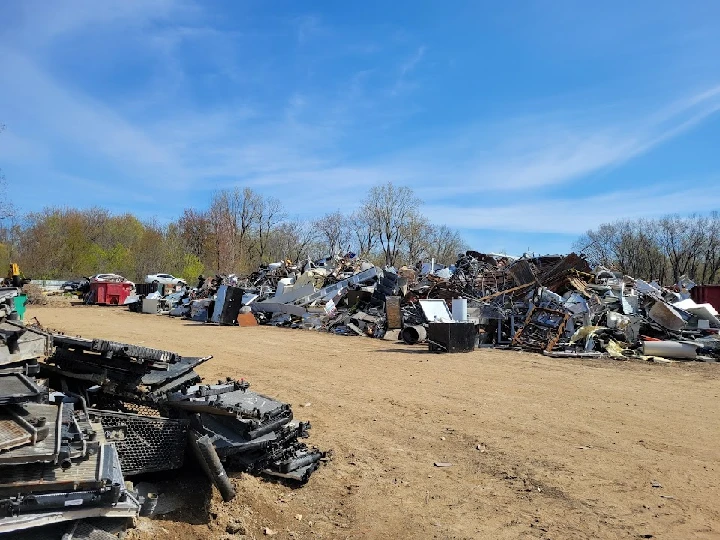 Scrap yard with piled metal and electronic debris.