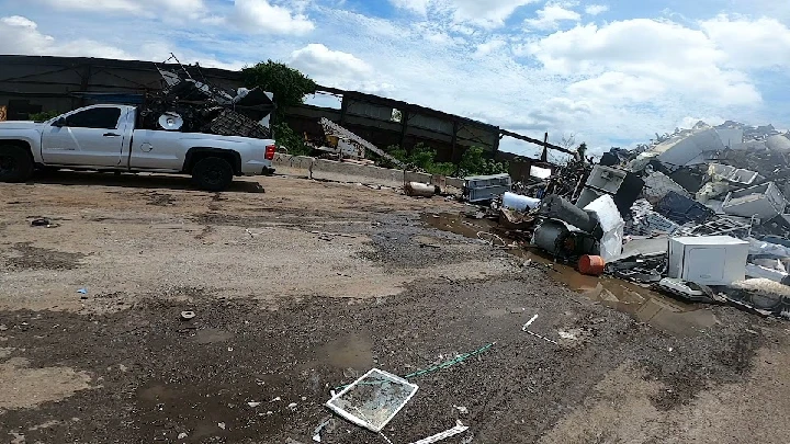 Scrapyard scene with truck and piles of debris.