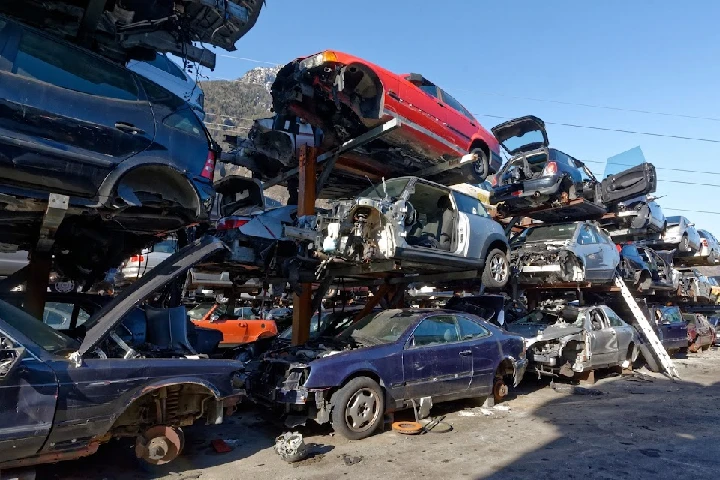 Scrapyard with stacked dismantled vehicles.