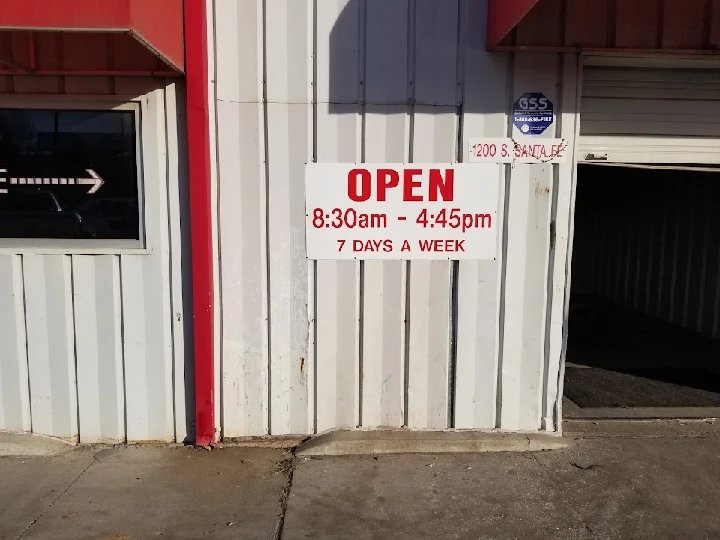 Sign indicating open hours for auto parts yard.