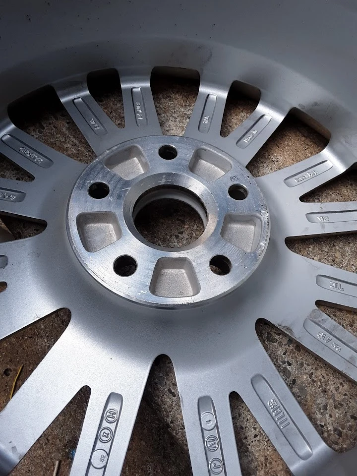 Silver alloy wheel close-up on a textured surface.