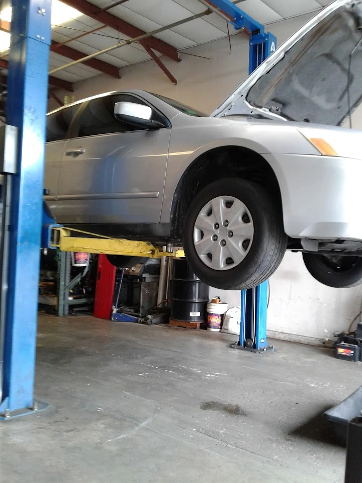 Silver car lifted for maintenance in auto shop.