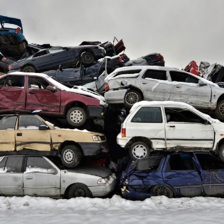 Stack of junk cars in a snowy junkyard.