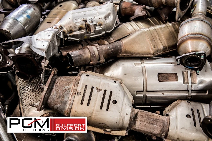 Stack of used catalytic converters and exhaust parts.