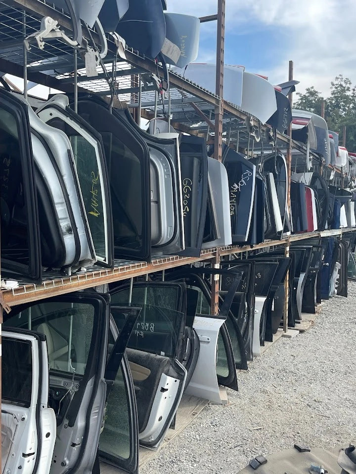 Stacked vehicle doors in an auto parts lot.