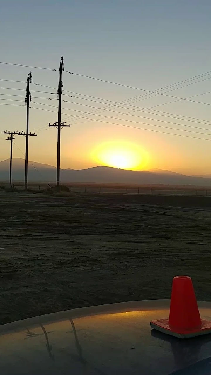 Sunset over a dismantling yard with power lines.