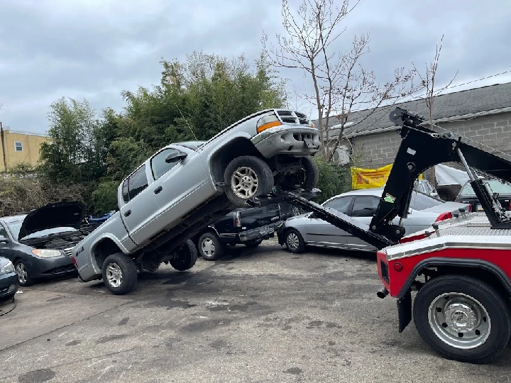 Tow truck lifting a junk car for removal.