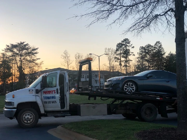 Tow truck loading a car at sunset. Manny's Towing.