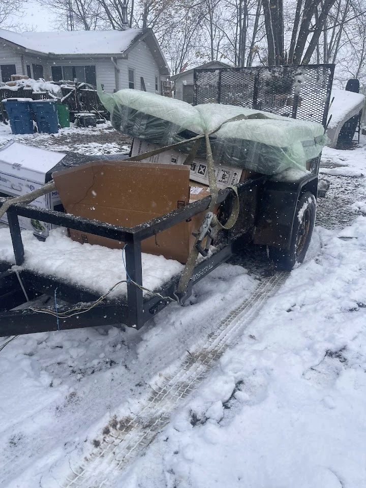 Trailer filled with junk on a snowy day.