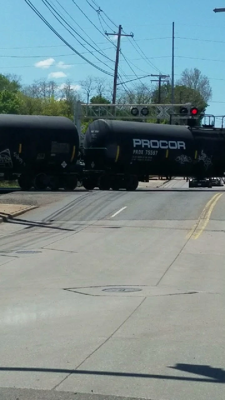 Train cars crossing a railroad track on a sunny day.