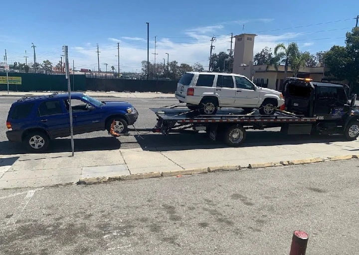 Two cars being towed on a flatbed truck.