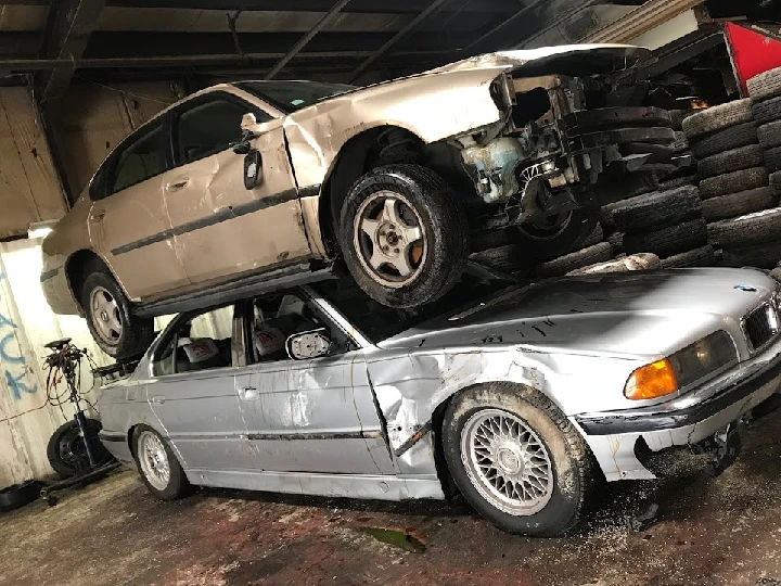 Two junk cars stacked in a garage.