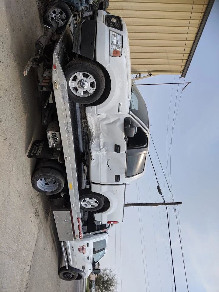 Two white trucks loaded on a tow truck. Auto wrecking.